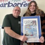 Harborfest Executive Director Dan Harrington presents a check and a framed print of the 2025 Harborfest poster to Brenna Riley, who created the winning poster entry.